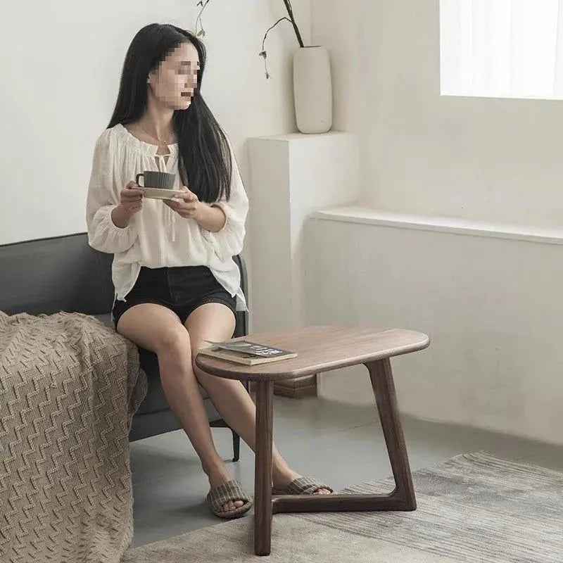 Modern wooden coffee table with a woman relaxing in a living room, holding a cup and saucer.