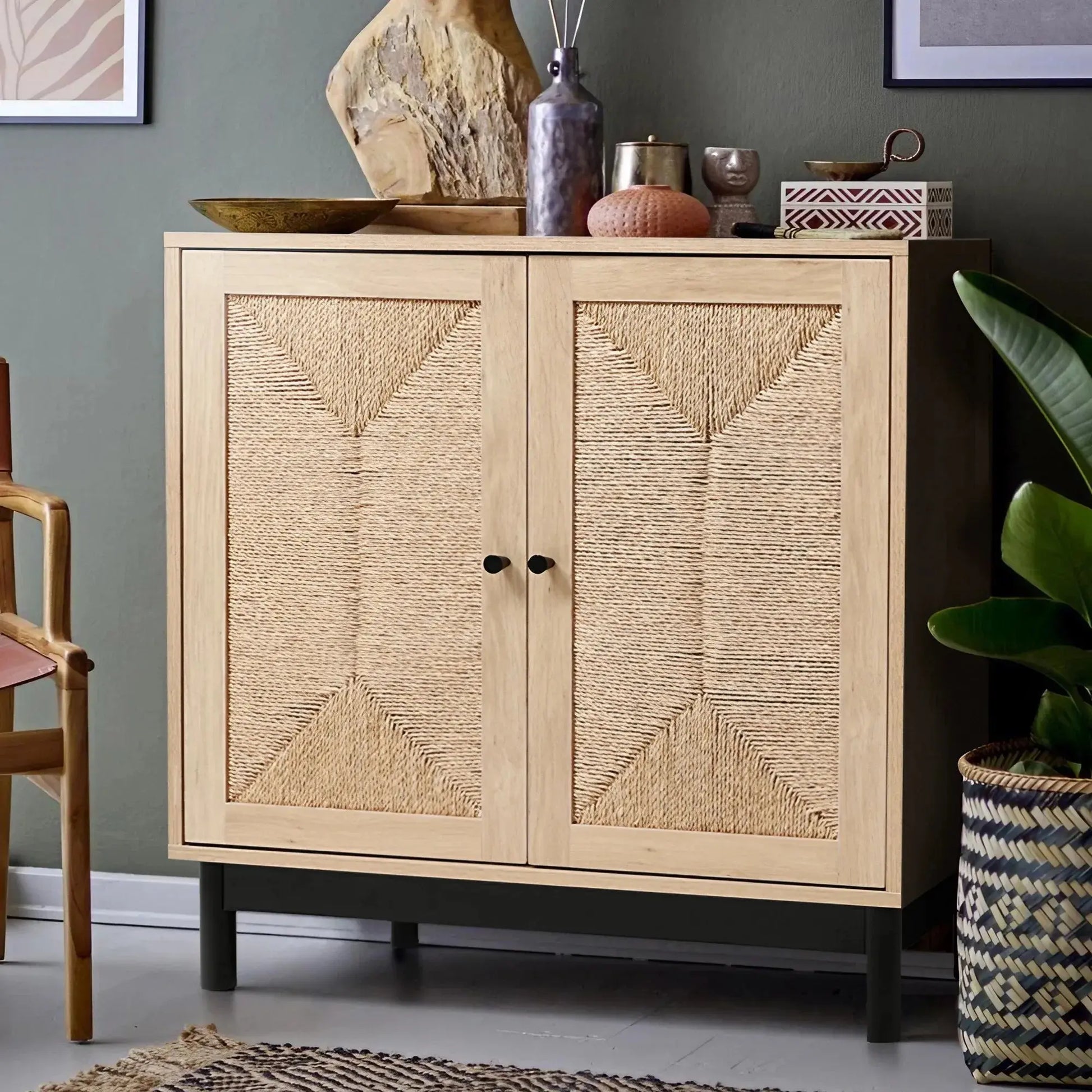 Rattan double door wooden sideboard with woven fronts, black handles, and metal base in a living room.