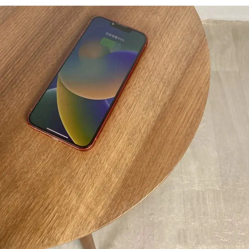 Round wooden smart coffee table with a red smartphone charging wirelessly on its surface