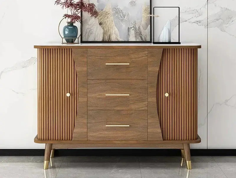 Modern minimalist wooden showcase cabinet with fluted doors, three central drawers, and golden pulls in a living room.