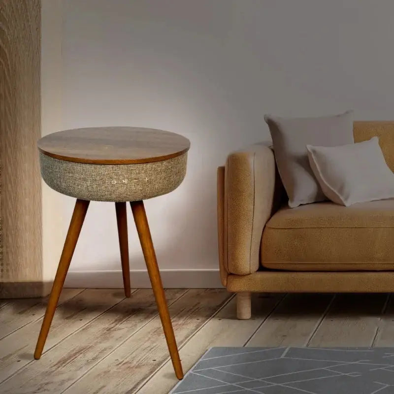 Round wooden smart coffee table with fabric sides and controls, next to a modern sofa in a living room.
