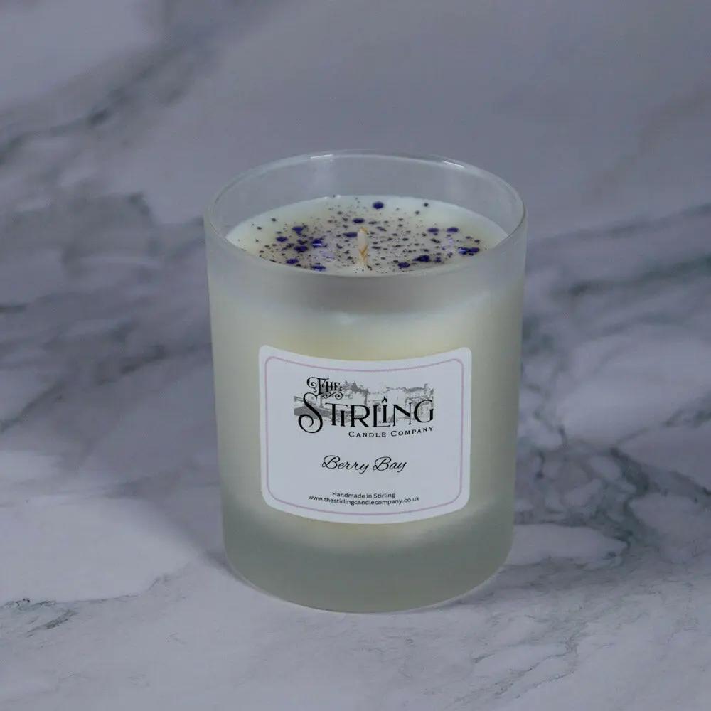 Berry Bay medium scented candle with white wax, purple glitter, and "The Stirling Candle Company" label on marble