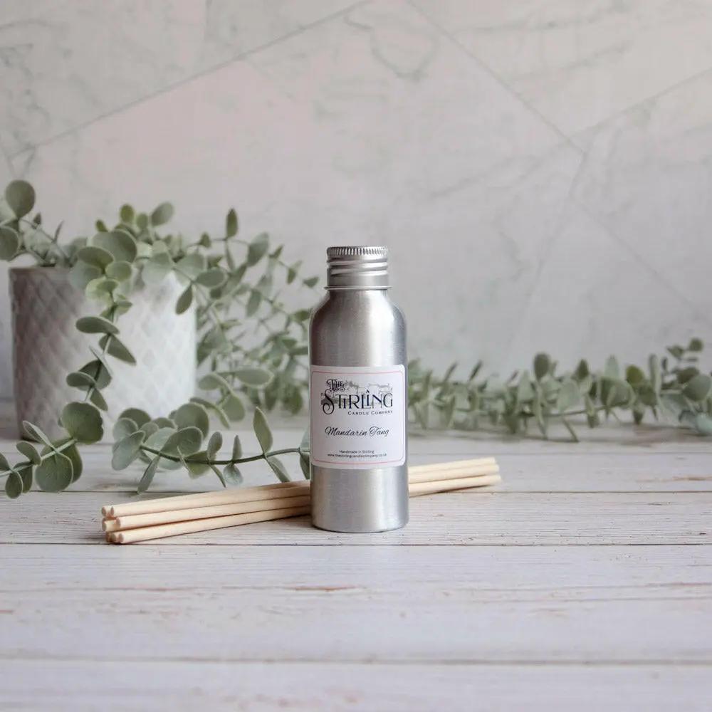 Mandarin Tang 100ml diffuser refill bottle with reeds on a wooden surface, next to a plant.