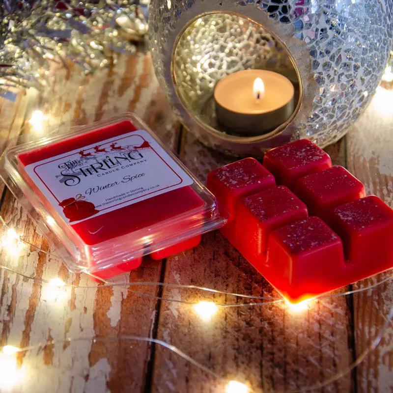 Red Winter Spice wax melt clamshell & six wax cubes beside a lit tealight in a mosaic burner with fairy lights.