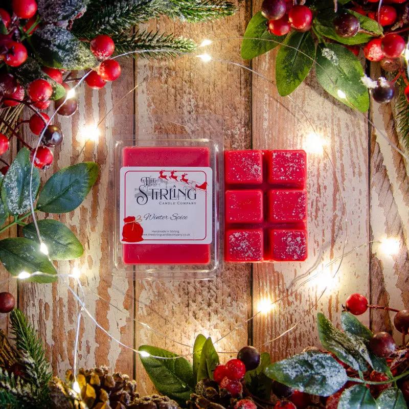Winter Spice wax melt clamshell & six individual red wax melts on a rustic wooden background with festive fairy lights.
