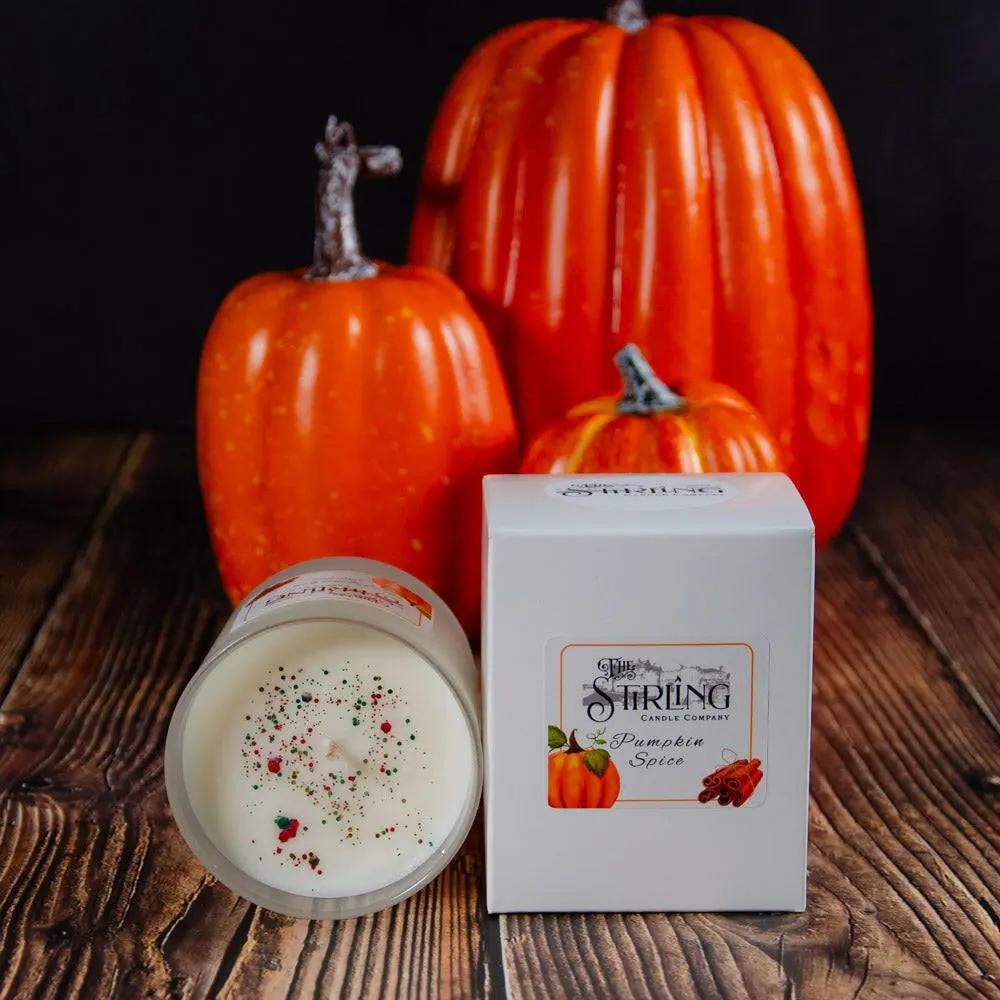 Pumpkin Spice medium candle, handmade in Stirling, Scotland, with sustainable rapeseed and coconut wax. Beside its white box, on a wooden surface with decorative pumpkins in the background.