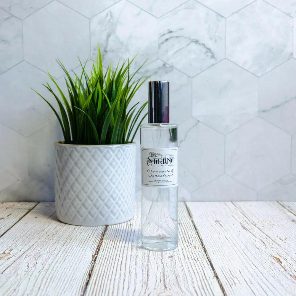 Chamomile & Sandalwood Room Spray 100ml clear glass bottle with black cap next to a potted plant