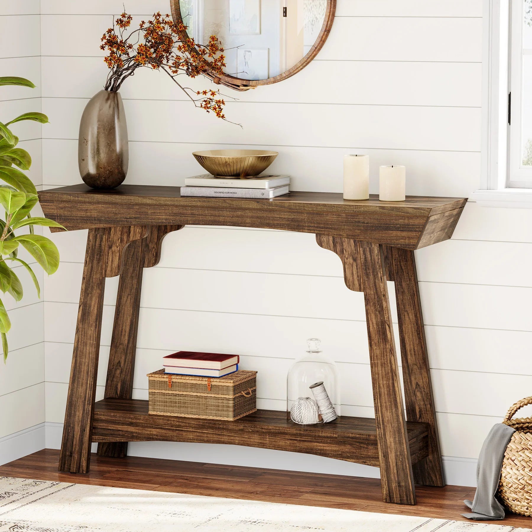 Rustic brown 2-tier entryway table with decorative vase, books, and candles in a living room.
