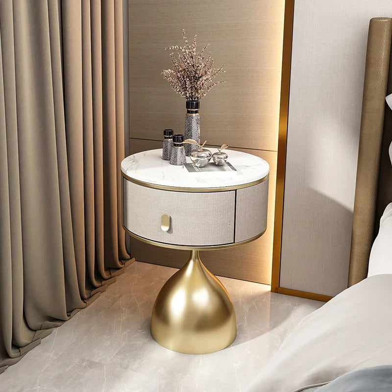 Luxury unique gold nightstand with marble top & fabric drawer in a modern bedroom setting. Premium bedside table.