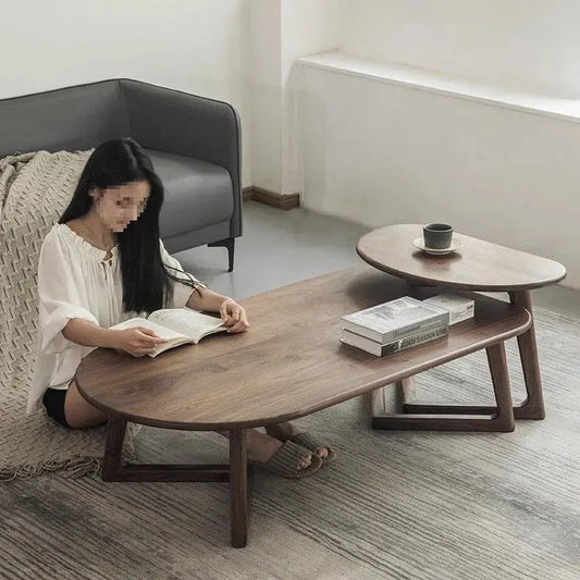 Modern wooden coffee table with a woman reading beside it and a smaller moving table with a cup.
