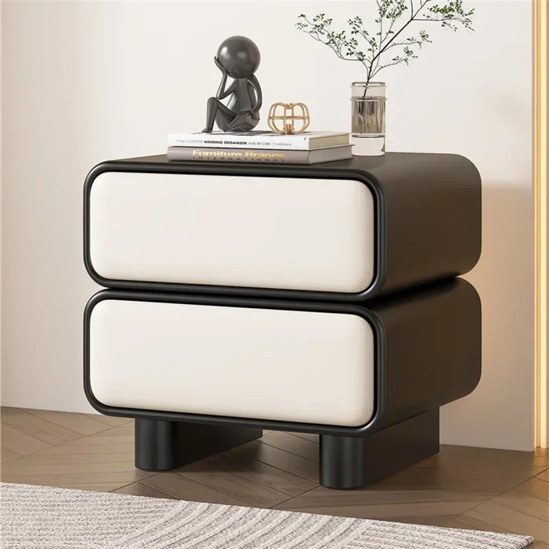 Modern Moroccan bedside table with two white drawers, black frame, and short black legs, shown in a bedroom.
