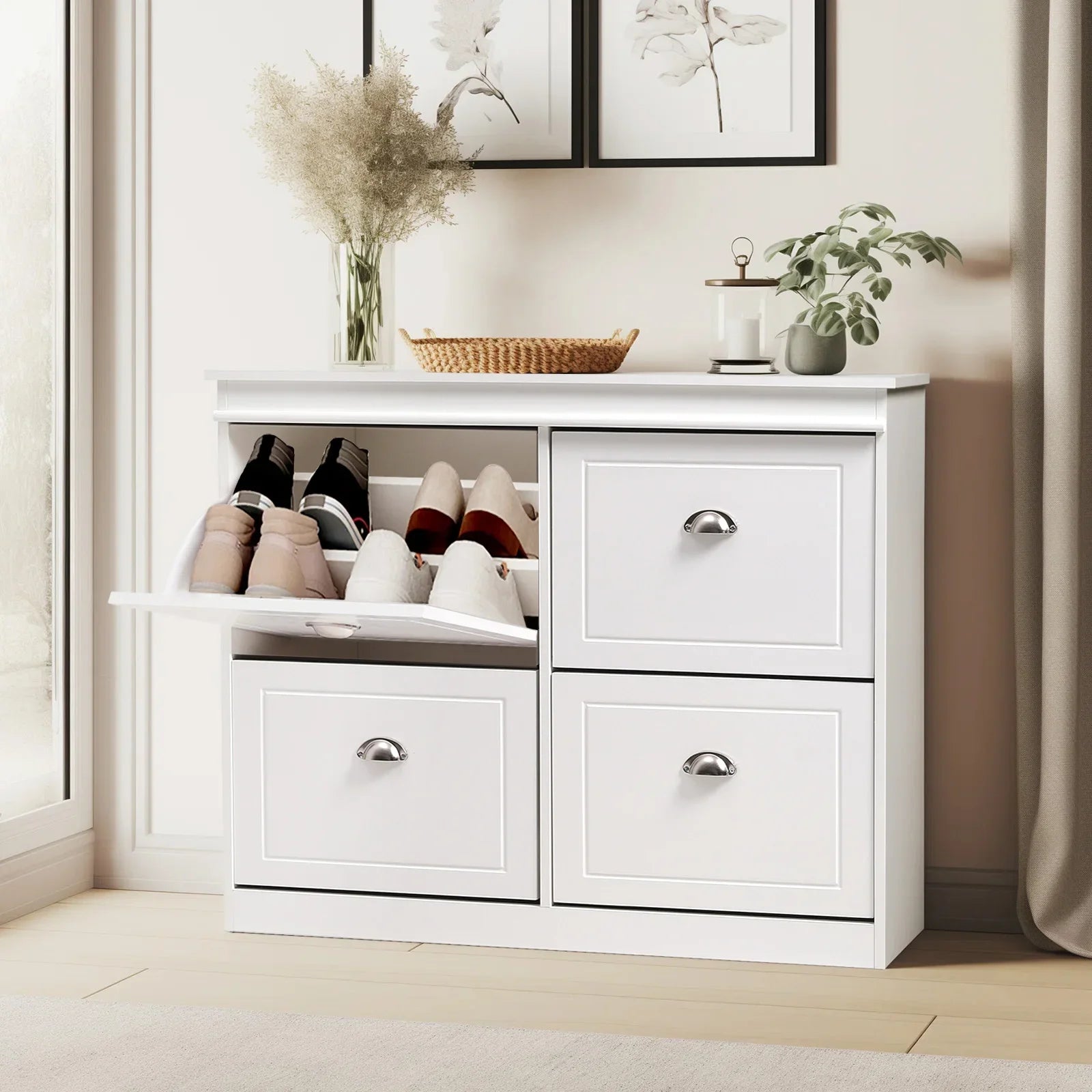 White flip-top shoe cabinet in an entryway, with one compartment open displaying shoes and three closed drawers.