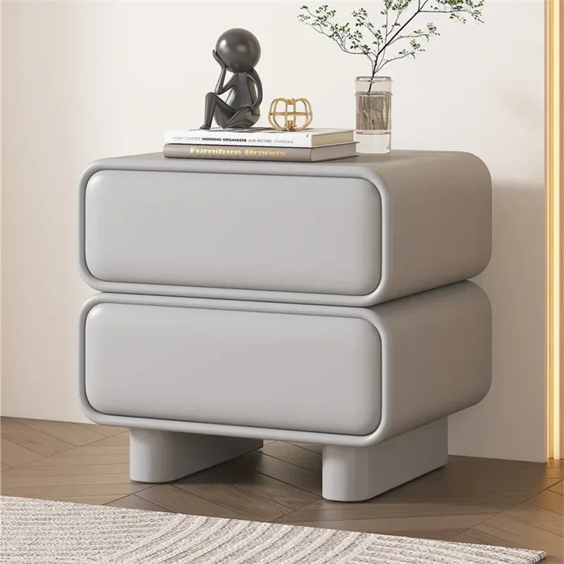 Grey modern Moroccan bedside table with two drawers, solid wood construction, and rounded edges in a bedroom.
