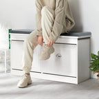 Person tying shoelaces on a white flip-top shoe cabinet with a grey cushion, ideal for entryway shoe storage.
