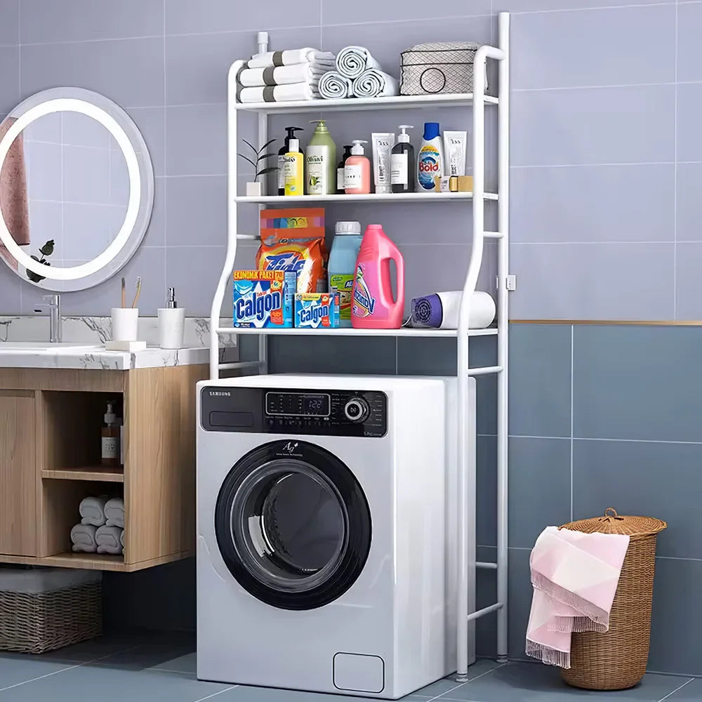 White 3-tier over washing machine storage rack in a modern bathroom, holding towels, toiletries, and laundry supplies