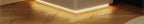 Close-up of a modern white nightstand with a subtle LED light strip illuminating the wooden floor below it.