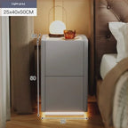 Grey rustic nightstand with integrated LED lighting, shown next to a bed with a lamp and teacup on top.