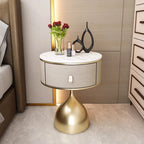 Luxury unique gold nightstand with marble top, fabric drawer, and sleek gold base, next to a bed.