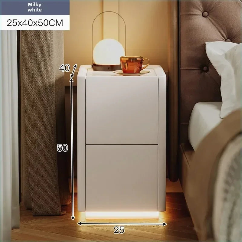 Milky white modern nightstand in a bedroom with ambient lighting. It features two drawers and bottom LED lighting.