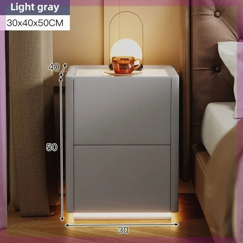 Light gray modern nightstand with two drawers, illuminated base, and dimensions 30x40x50cm next to a bed