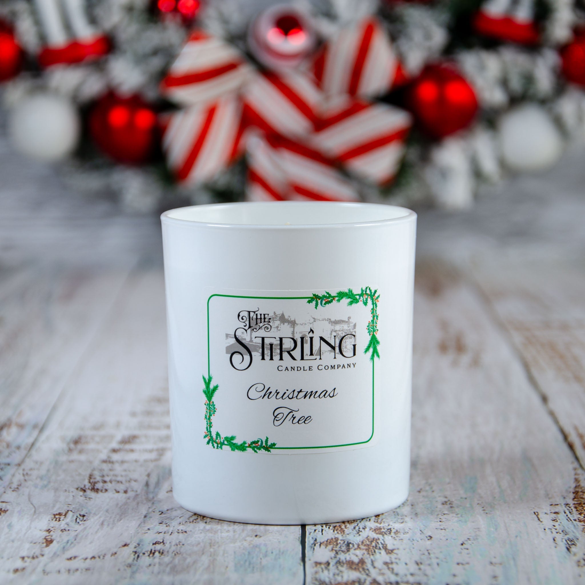 Large Christmas Tree candle by The Stirling Candle Company with festive label on wood, holiday decor in background