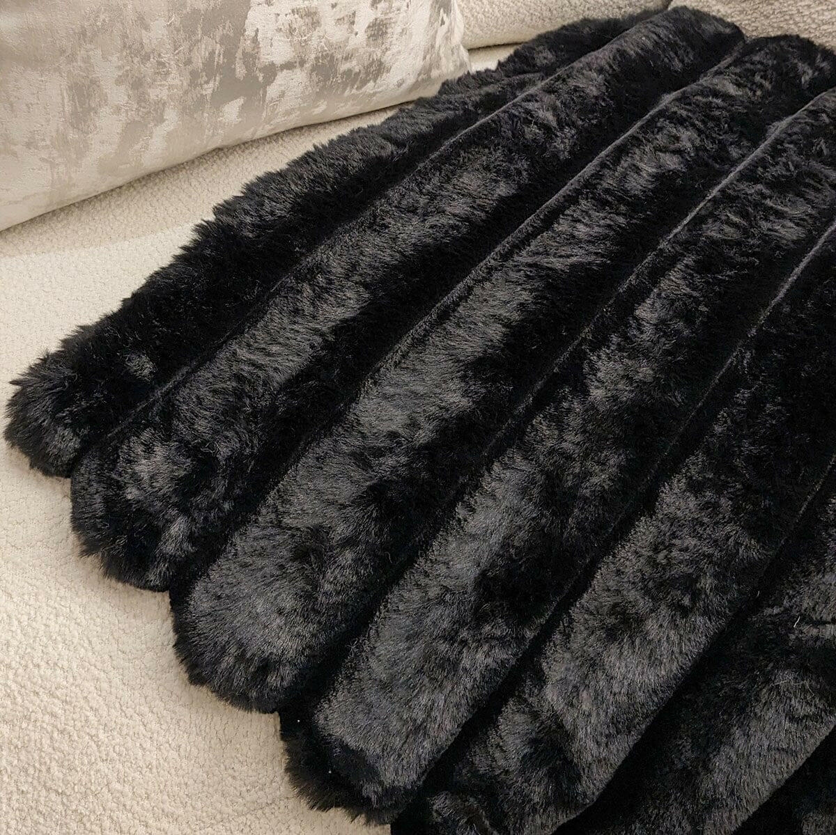 Isla black chunky ribbed faux fur throw on a sofa, showcasing plush texture and luxurious design.