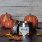 Pumpkin Spice Travel Tin candle, lid ajar, with autumn pumpkins and leaves in background for a cosy feel.