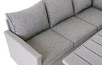 Close-up of Stockholm 6-seater grey rattan garden corner sofa with comfortable grey cushions and part of dining table.