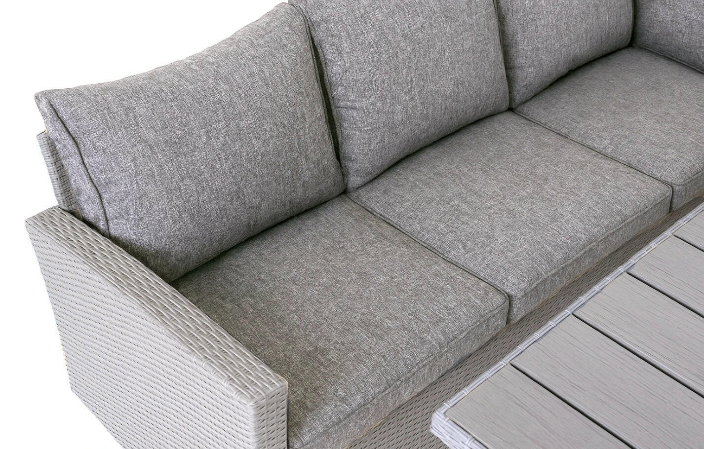 Close-up of Stockholm 6-seater grey rattan garden corner sofa with comfortable grey cushions and part of dining table.