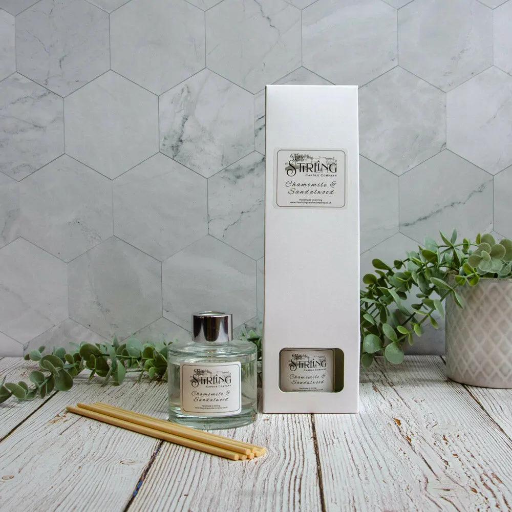 Chamomile & Sandalwood 100ml diffuser bottle and white box, with reeds and plants on a wooden table.