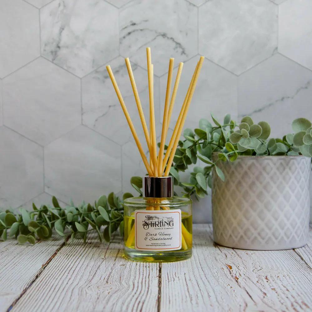 Dark Honey & Sandalwood 100ml diffuser with reeds, natural plant decor, and grey patterned pot on wooden surface.