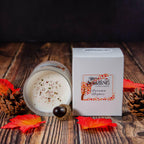 Autumn Nights Medium Candle with label and white box, showing glittery surface on wooden background.