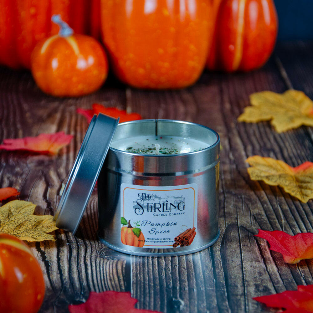 Pumpkin Spice Travel Tin candle with cotton wick, open lid, on wooden surface with autumn leaves and pumpkins