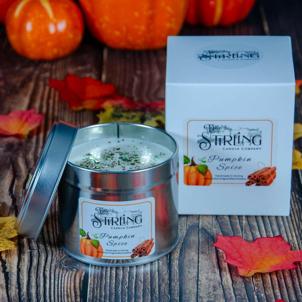 Pumpkin Spice Travel Tin candle with cotton wick, next to its white box, on a wooden surface with autumn decor