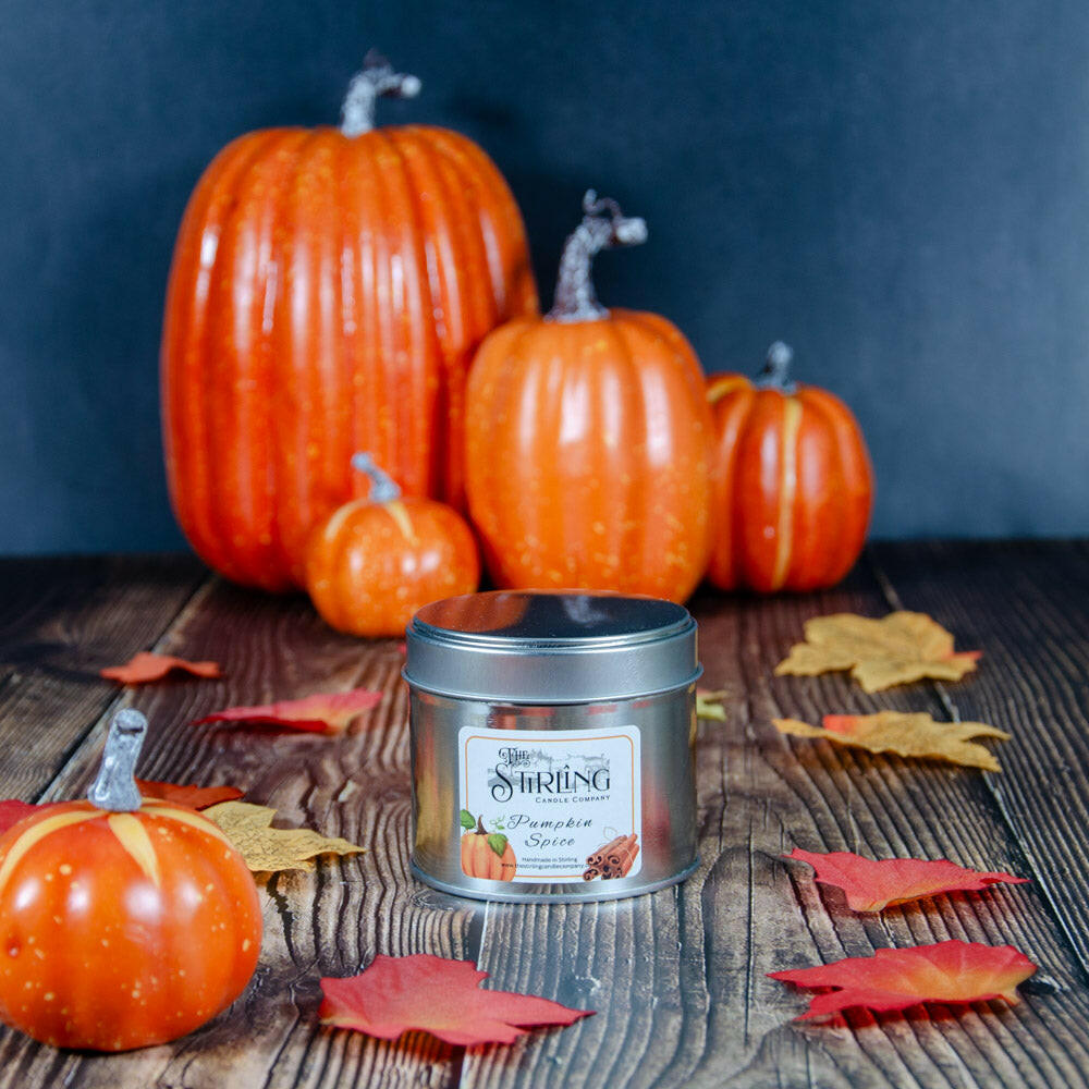 Pumpkin Spice Travel Tin candle with autumn leaves and decorative pumpkins on a wooden surface.