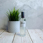 Beach Day Room Spray 100ml bottle with a green plant in a white pot on a wooden surface, luxury home fragrance