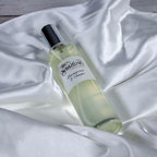 The Stirling Candle Company Lemongrass & Ginger 100ml room spray bottle on white satin fabric.