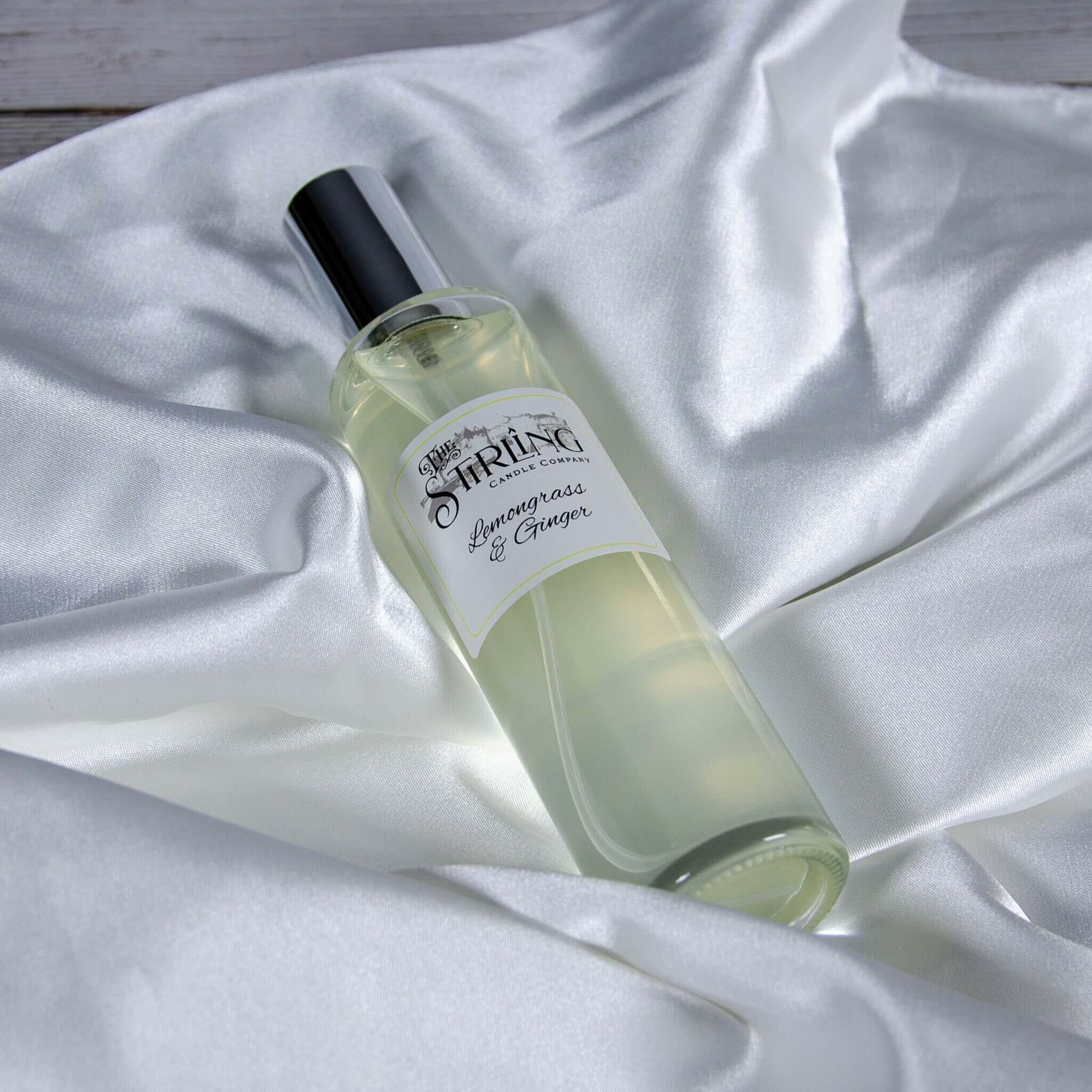 The Stirling Candle Company Lemongrass & Ginger 100ml room spray bottle on white satin fabric.